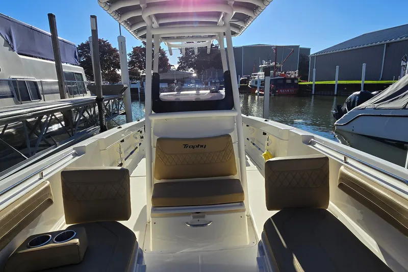 Slide: The Image of 2023 Bayliner Trophy T24CC boat interior at marina, showcasing seating and helm. - 25