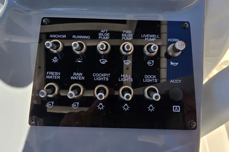 Slide: The Image of Control panel of 2023 Bayliner Trophy T24CC boat with labeled switches for various functions. - 17