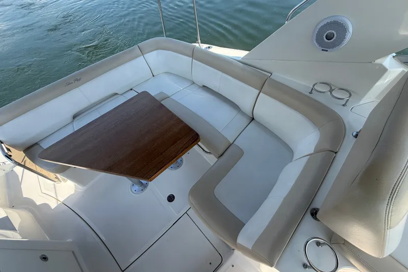 Slide: The Image of 2013 Sea Ray Sundancer 350 boat interior with cushioned seating and wooden table. - 23