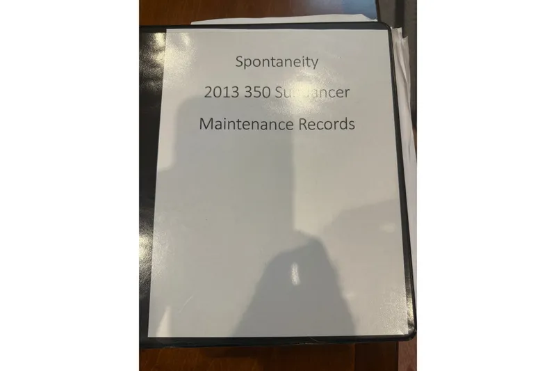Slide: The Image of Binder labeled "Spontaneity 2013 350 Sundancer Maintenance Records" on a table. - 63