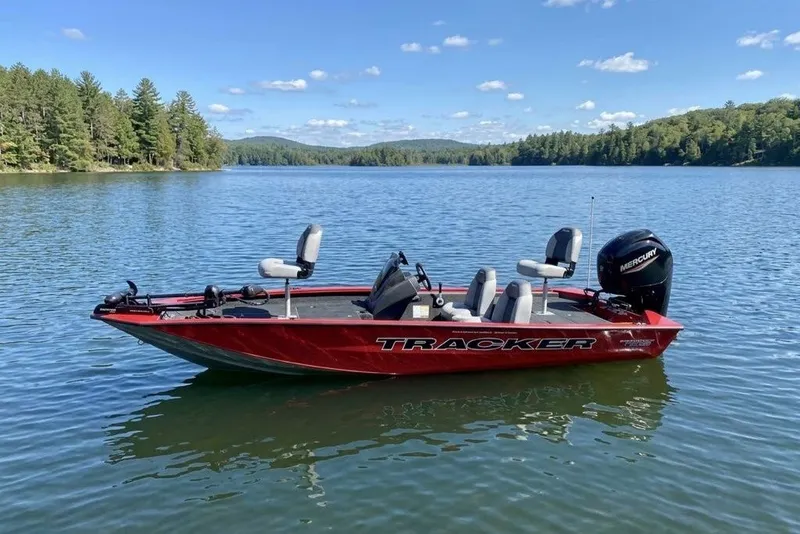 The Image of 2027 Tracker Pro Team 175 boat on a serene lake with forested shoreline. - 9