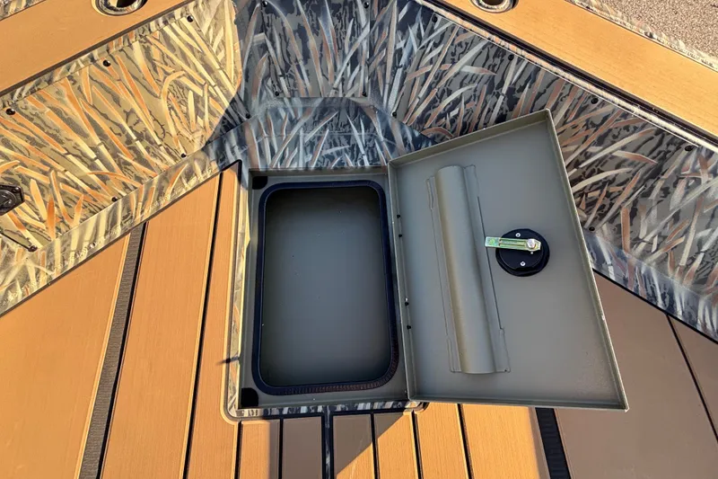 Slide: The Image of Open storage compartment on 2027 Tracker Grizzly 1756 T Marsh boat with camo design. - 16