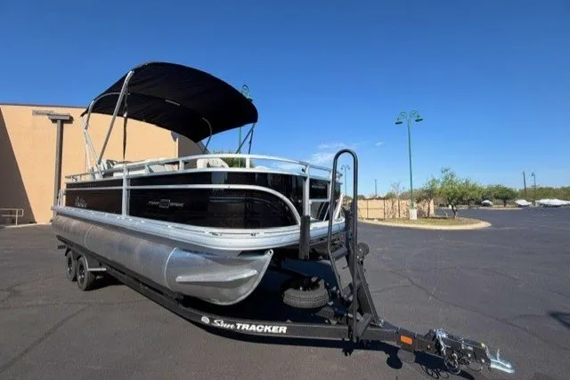 The Image of 2027 Sun Tracker Fishin' Barge 22 DLX pontoon boat on trailer, parked outdoors. - 0