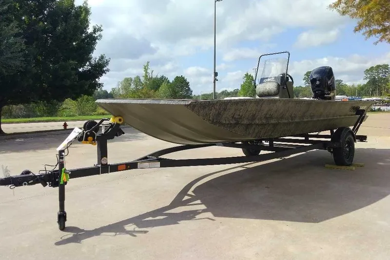 The Image of 2027 Tracker Grizzly 1860 CC boat on trailer, parked outdoors under cloudy sky. - 0