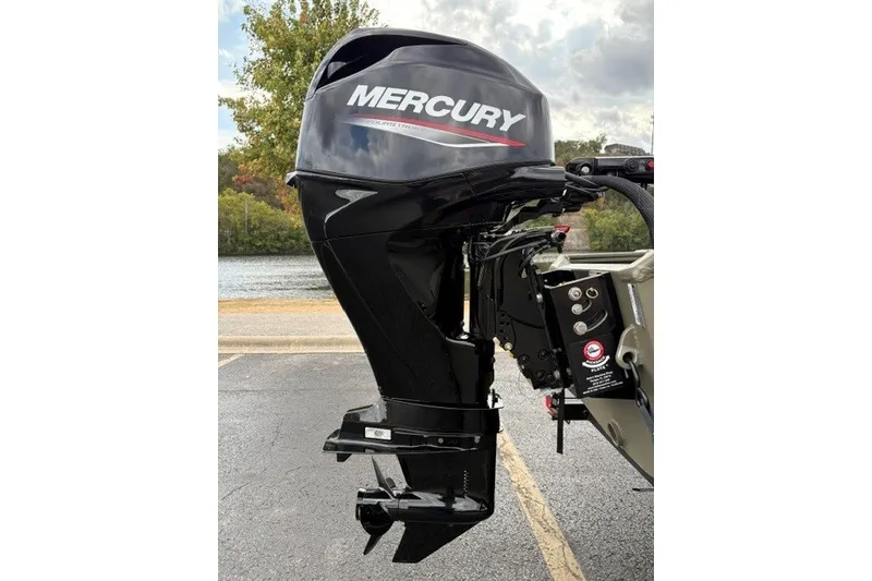 Slide: The Image of Outboard motor on a 2027 Tracker Grizzly 1553 Timber boat, parked near a lake. - 21