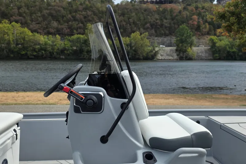 Slide: The Image of 2027 Tracker Bass Tracker Classic CC boat console with steering wheel by a scenic river. - 16