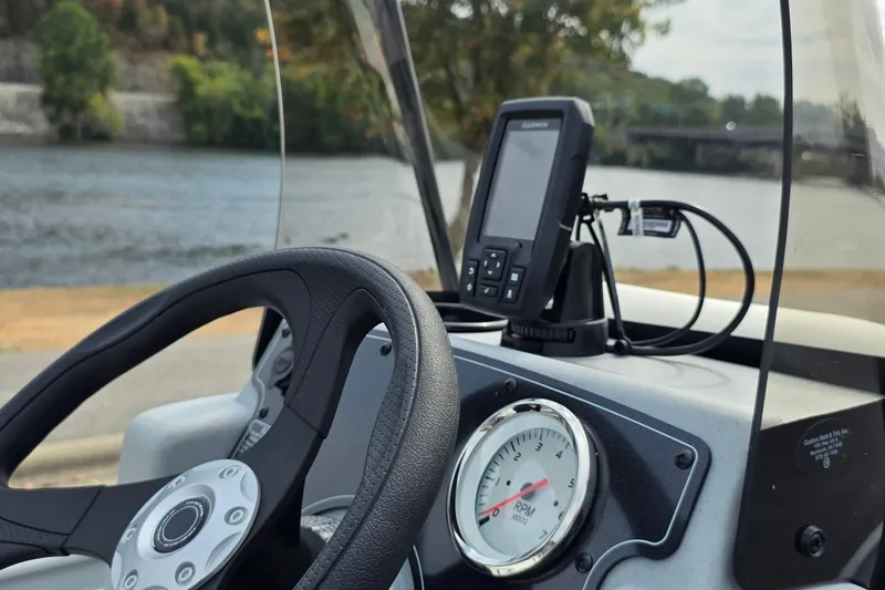 Slide: The Image of Steering wheel and dashboard of 2027 Tracker Bass Tracker Classic CC boat by a river. - 18