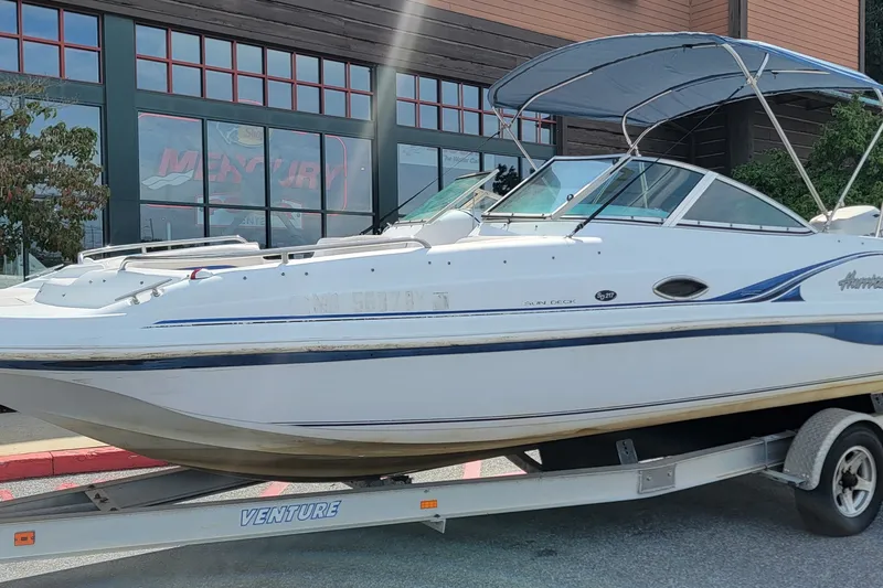 Slide: The Image of 2001 Hurricane SunDeck 217 OB boat on trailer, parked outside a building. - 5
