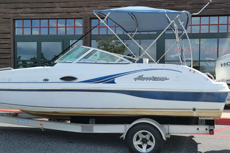 Slide: The Image of 2001 Hurricane SunDeck 217 OB boat on trailer, parked outside a building. - 4