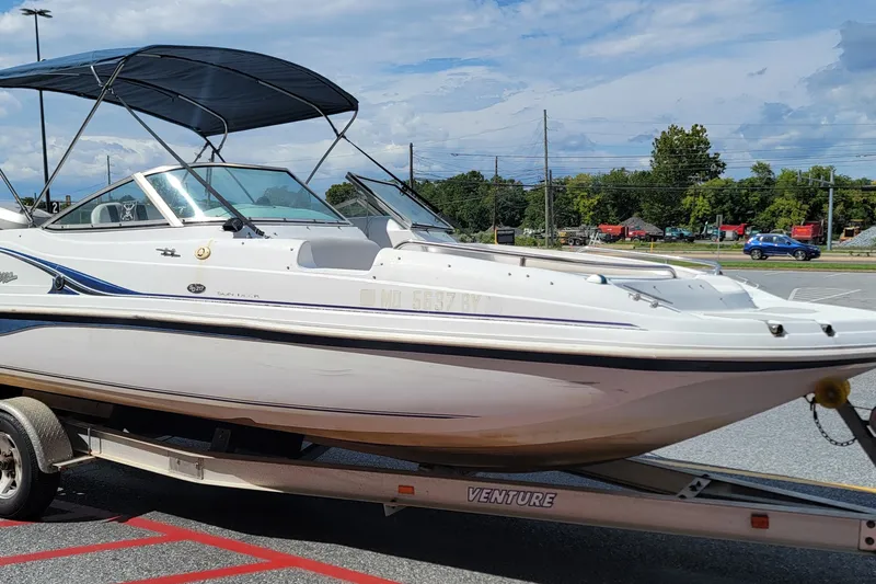Slide: The Image of 2001 Hurricane SunDeck 217 OB boat on trailer, parked outdoors under blue sky. - 23