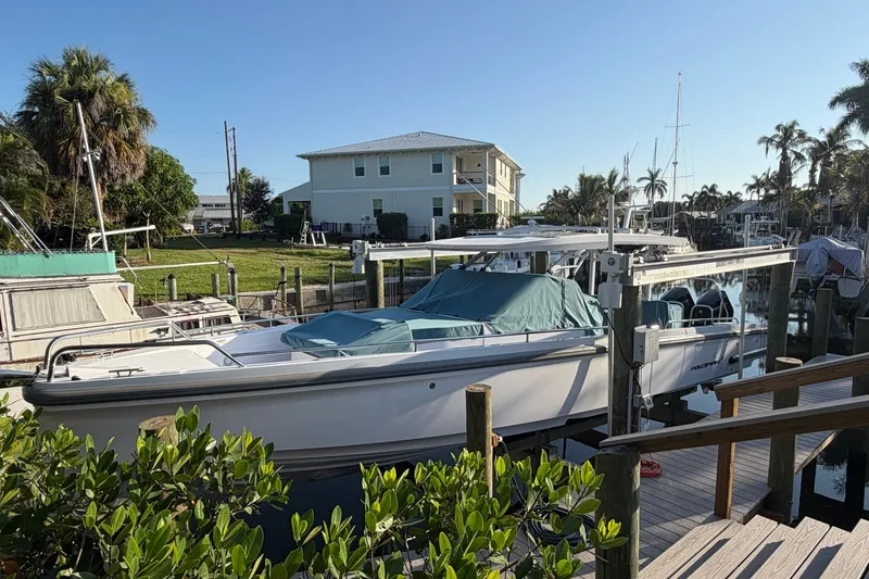 Slide: The Image of 2024 Axopar 37 Sun-Top boat docked near waterfront homes and lush greenery. - 15