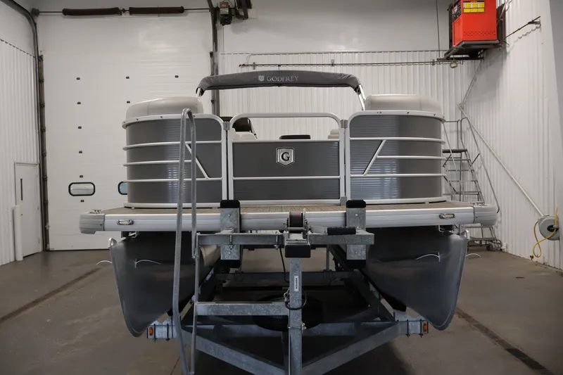Slide: The Image of 2021 Sweetwater 2086C pontoon boat in a garage, front view on a trailer. - 1