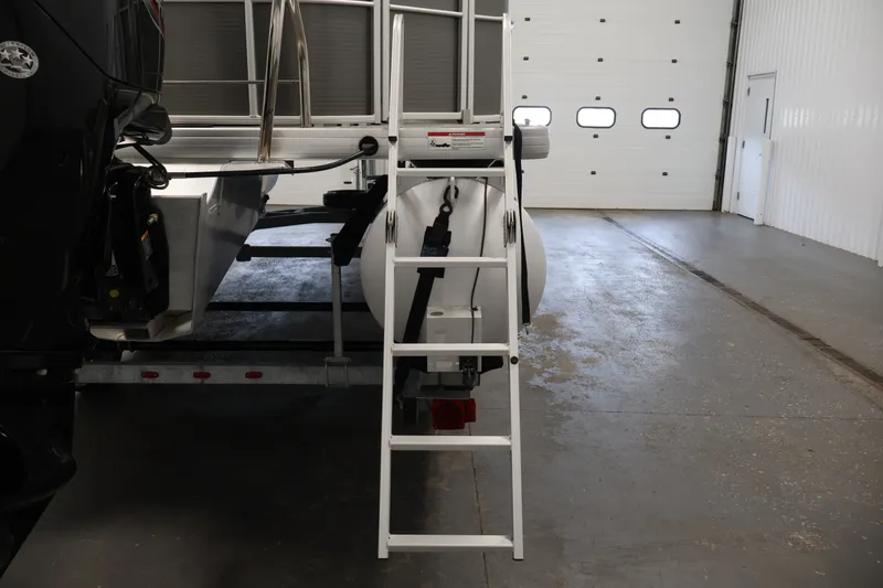 Slide: The Image of 2021 Sweetwater 2086C pontoon boat with ladder in a spacious indoor garage. - 31