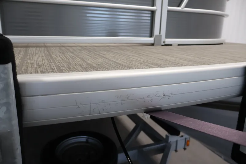 Slide: The Image of 2021 Sweetwater 2086C pontoon boat deck with visible scratches and trailer. - 42