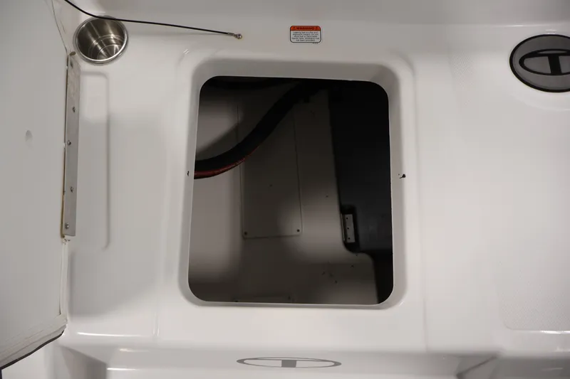 Slide: The Image of 2022 Tahoe T18 boat storage compartment with cup holder and warning label. - 31
