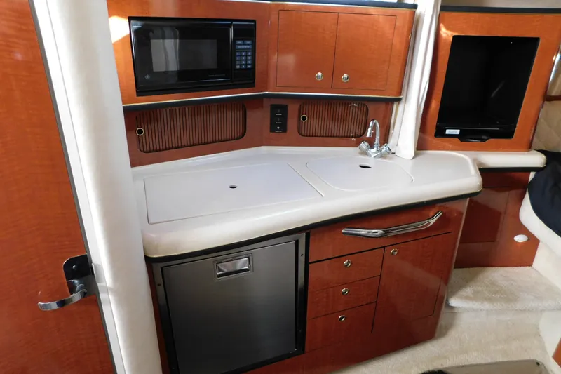 Slide: The Image of 2001 Sea Ray 300 Sundancer interior kitchen with microwave, sink, and cabinetry. - 45