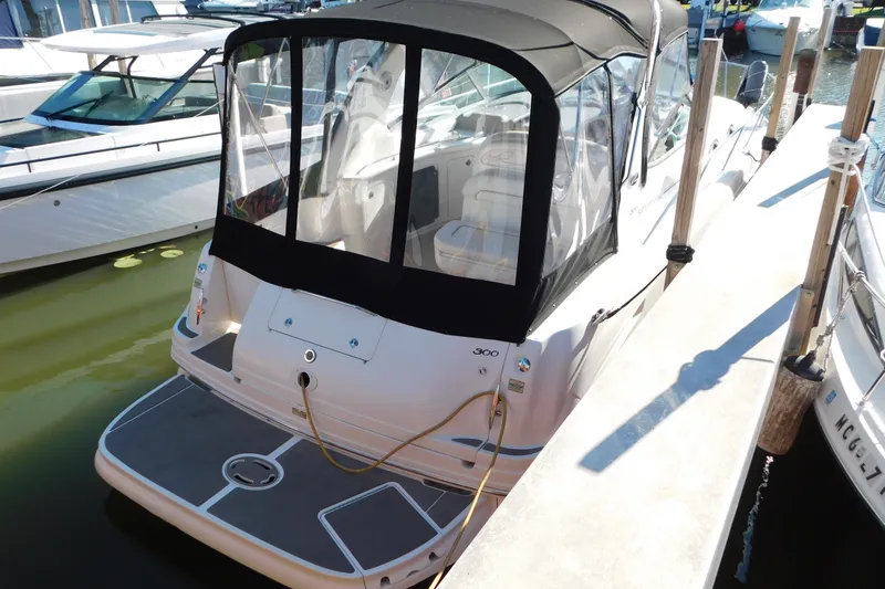 Slide: The Image of 2001 Sea Ray 300 Sundancer docked, featuring a black canopy and spacious deck. - 3