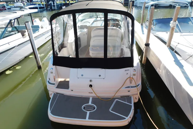 Slide: The Image of 2001 Sea Ray 300 Sundancer docked, featuring a covered cockpit and spacious deck area. - 2