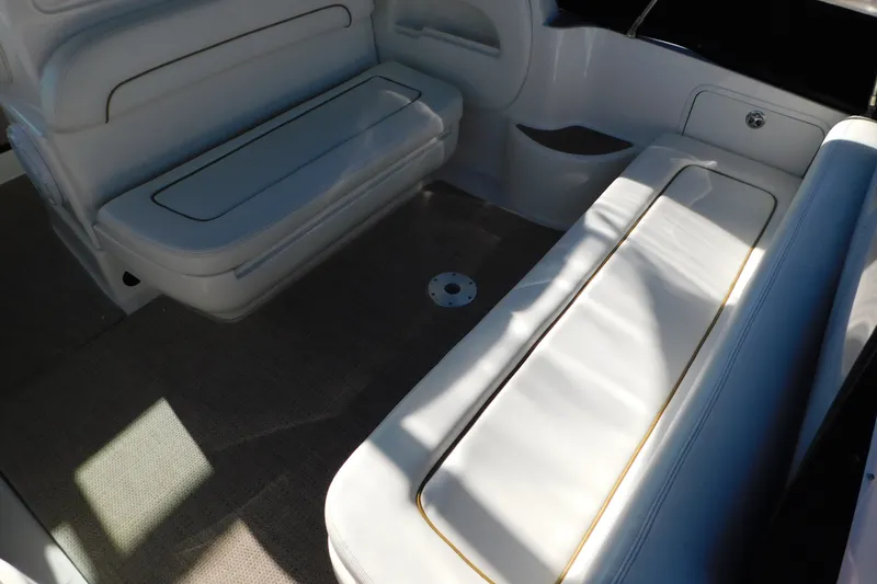 Slide: The Image of Interior seating of 2001 Sea Ray 300 Sundancer boat, featuring white cushioned benches. - 16