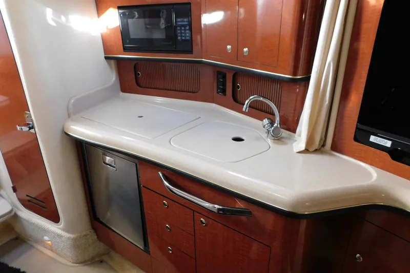 Slide: The Image of 2001 Sea Ray 300 Sundancer kitchen with sink, microwave, and wooden cabinetry. - 49