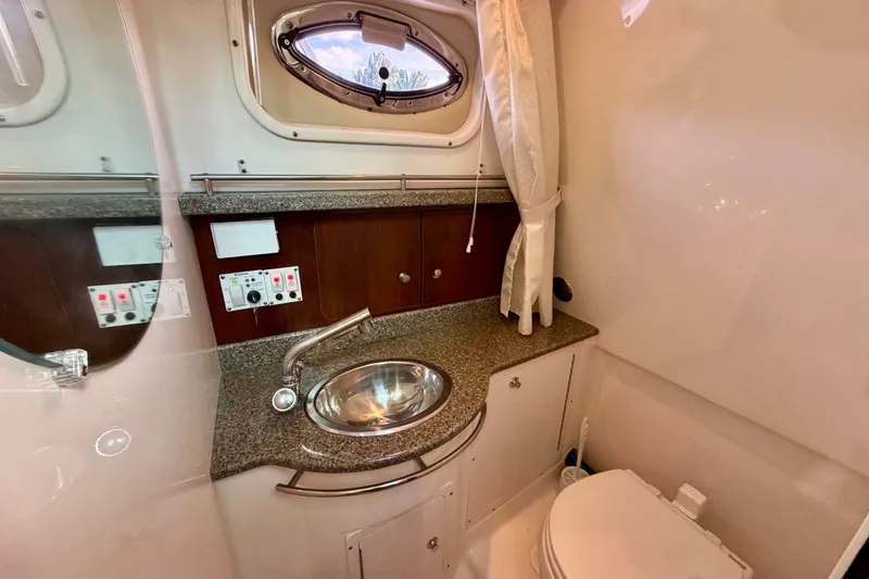 Slide: The Image of 2014 Robalo R305 Walkaround bathroom with sink, toilet, and porthole window. - 26