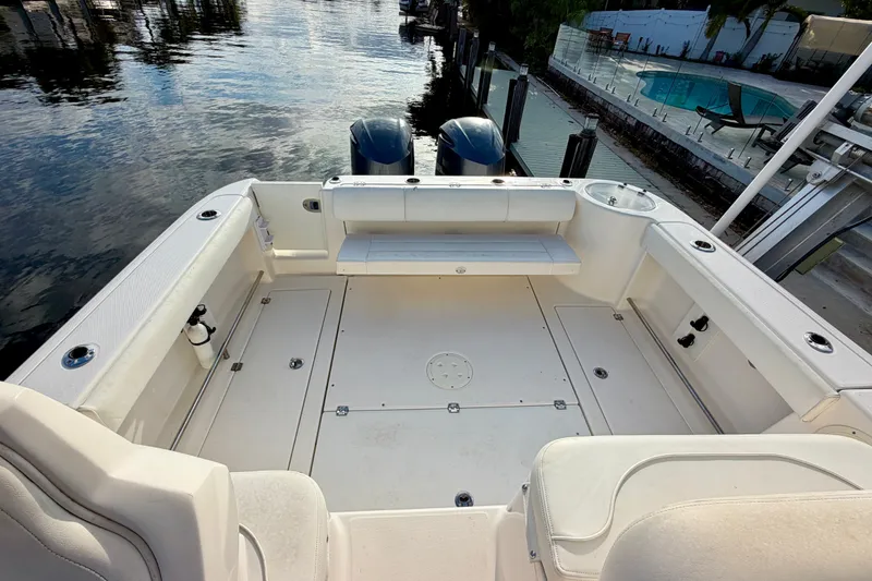 Slide: The Image of 2014 Robalo R305 Walkaround boat deck with seating, docked by a waterfront. - 20