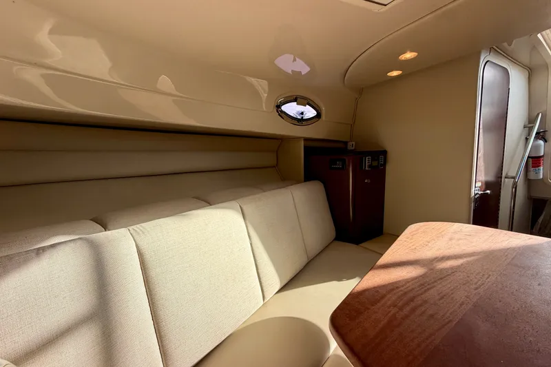 Slide: The Image of Interior of 2014 Robalo R305 Walkaround boat with beige seating and wooden table. - 24