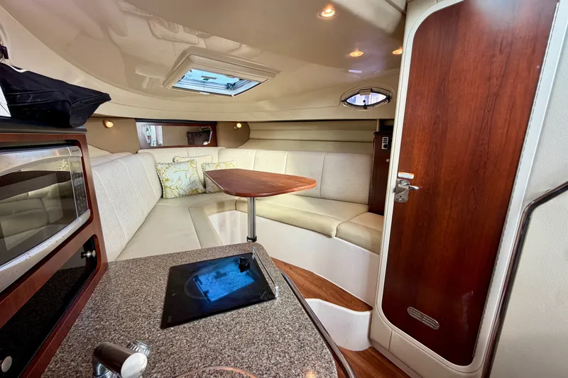Slide: The Image of 2014 Robalo R305 Walkaround cabin interior with seating, table, and kitchenette. - 22