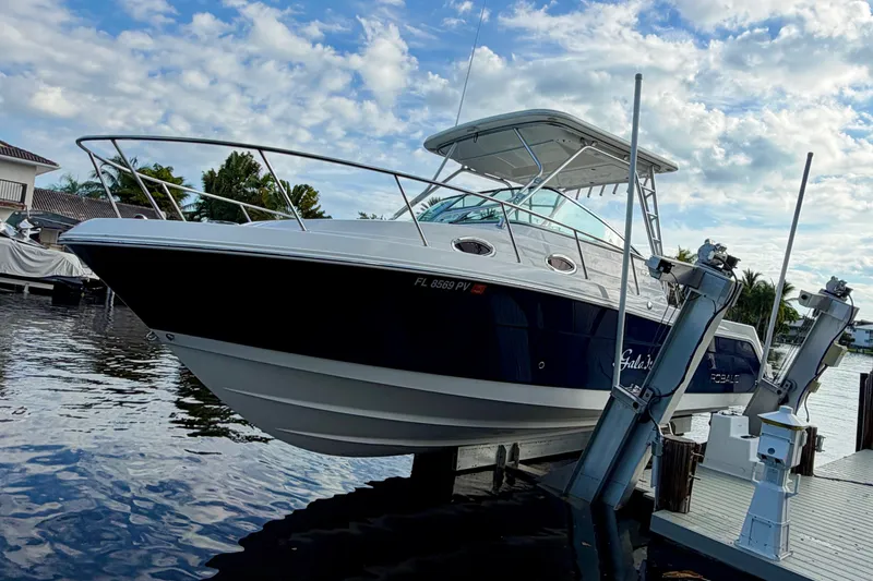 The Image of 2014 Robalo R305 Walkaround boat docked by waterfront under cloudy sky. - 0