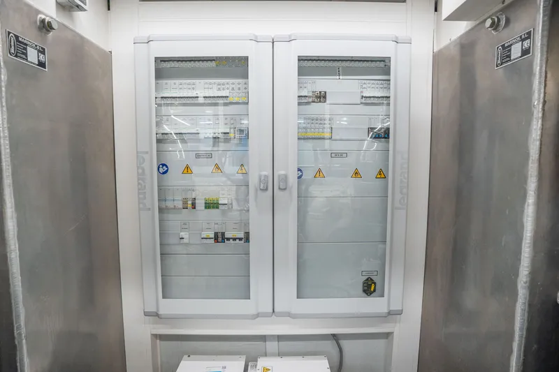 Slide: The Image of Electrical panel inside 2022 Astondoa 66 Fly yacht, featuring safety warnings and control switches. - 53