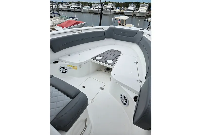 Slide: The Image of 2025 NauticStar 252 Legacy boat interior with seating and table, docked at marina. - 4