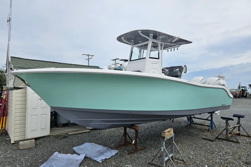 The Image of 2025 NauticStar 252 Legacy boat on stands, light blue hull, overcast sky. - 0