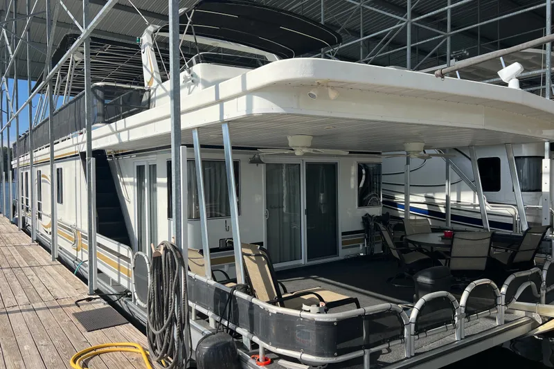 Slide: The Image of 1999 Fantasy 75' x 17' Custom houseboat docked, featuring spacious deck and outdoor seating. - 2