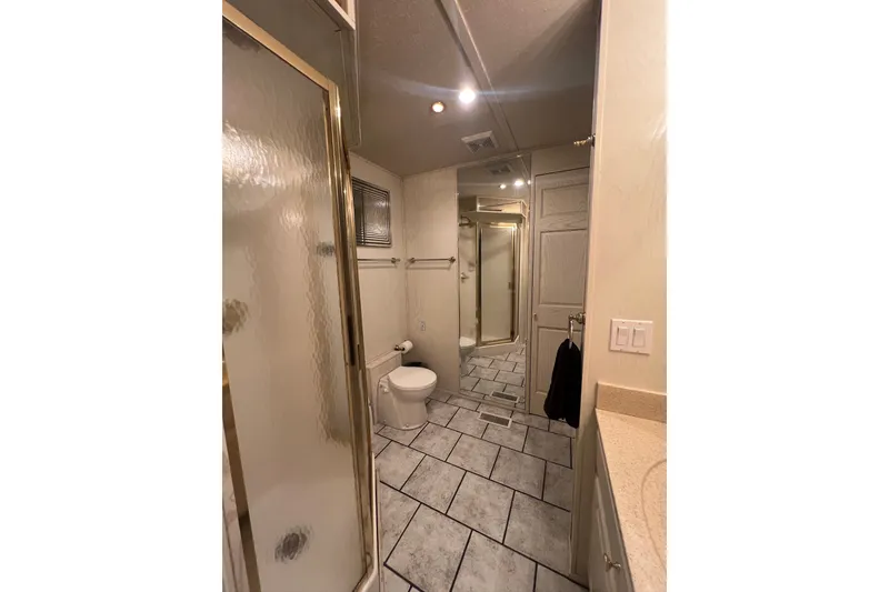 Slide: The Image of Luxurious bathroom in a 1999 Fantasy Custom houseboat, featuring tiled floor and glass shower. - 44