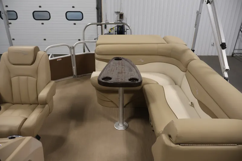 Slide: The Image of 2017 Bennington 21 SL pontoon boat interior with beige seating and central table. - 25
