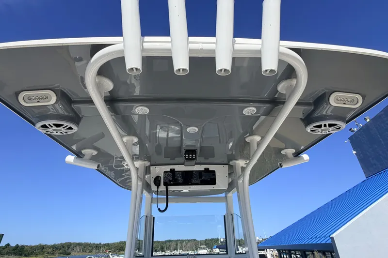 Slide: The Image of 2025 NauticStar 251 Hybrid boat roof with speakers and rod holders against blue sky. - 15