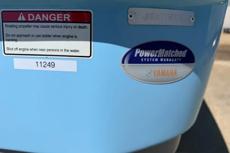 Slide: The Image of 2025 NauticStar 251 Hybrid boat stern with safety warning and Yamaha warranty sticker. - 16