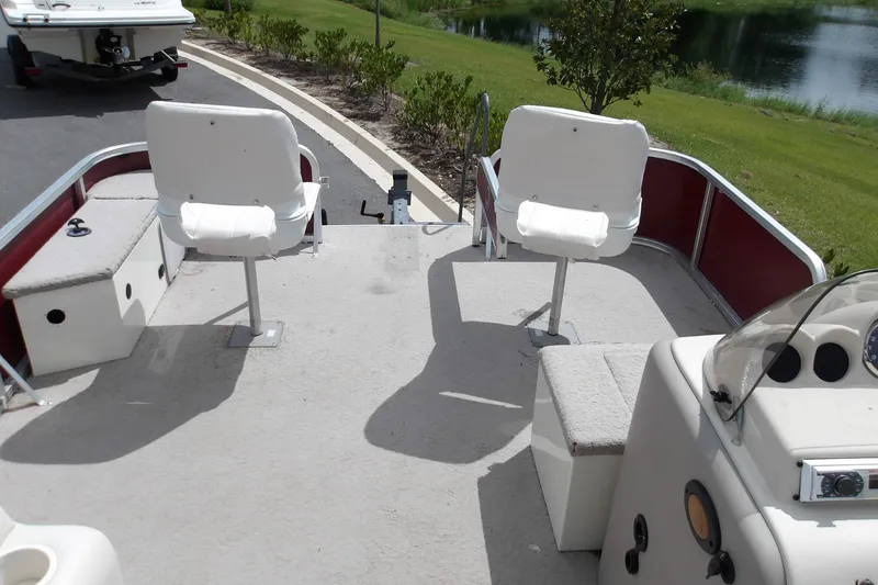 Slide: The Image of 2010 Lowe SF 194 Sport Fish boat interior with swivel seats and console, near a lake. - 4