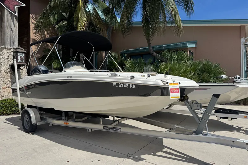 The Image of 2016 NauticStar 203 SC boat on trailer, displayed outdoors with palm trees. - 1