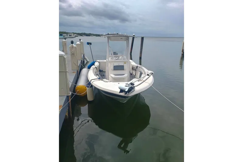 Slide: The Image of 2019 Tidewater 210 CC Adventure boat docked on calm water under cloudy skies. - 10