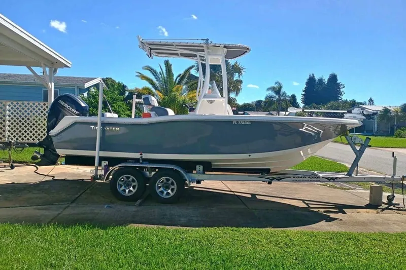 Slide: The Image of 2019 Tidewater 210 CC Adventure boat on trailer, parked in a sunny residential area. - 2