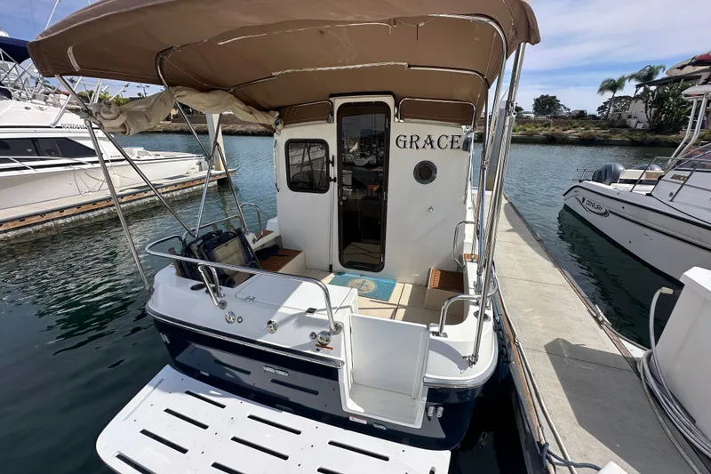 Slide: The Image of 2009 Ranger Tugs R-25 boat docked, featuring a covered deck and rear entry. - 7