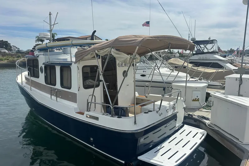 Slide: The Image of 2009 Ranger Tugs R-25 boat docked at marina, featuring blue hull and canopy. - 5
