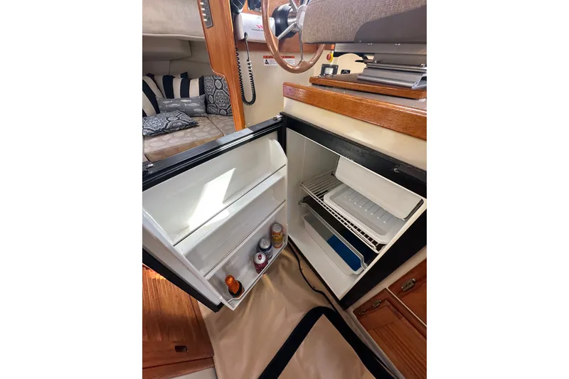 Slide: The Image of 2009 Ranger Tugs R-25 interior with open mini fridge and cozy seating area. - 26