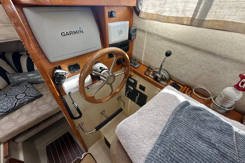 Slide: The Image of 2009 Ranger Tugs R-25 helm with Garmin navigation, wooden steering wheel, and cozy cabin interior. - 24