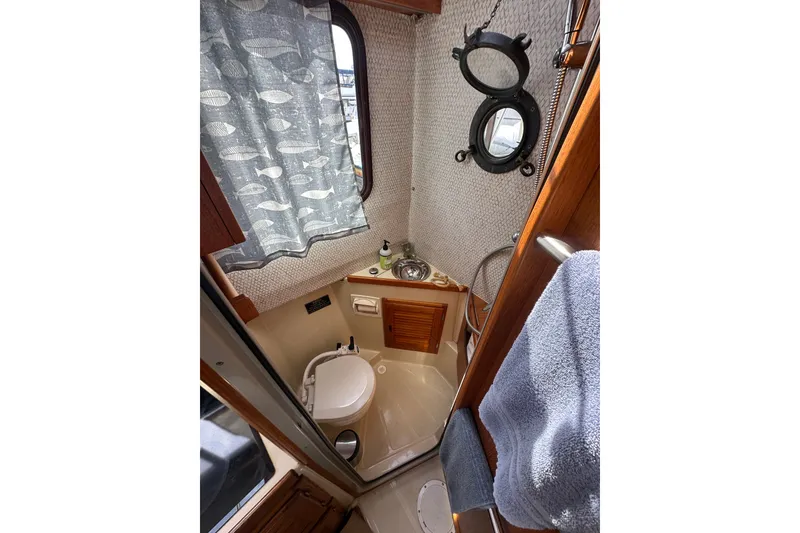 Slide: The Image of Compact bathroom in 2009 Ranger Tugs R-25 boat with nautical decor and porthole window. - 30