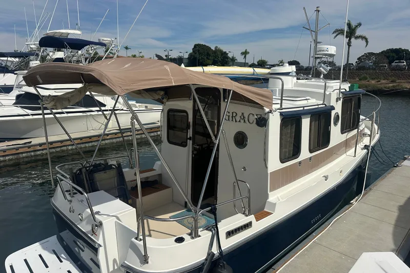 Slide: The Image of 2009 Ranger Tugs R-25 boat docked, featuring a beige canopy and sleek design. - 4