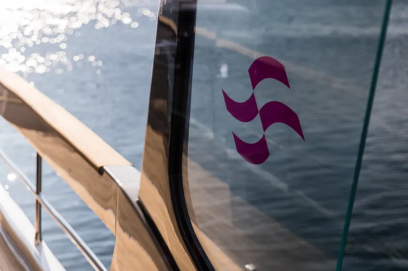 Slide: The Image of Sleek Sirena 78 yacht window with logo, reflecting sunlight on water, 2027 model. - 18