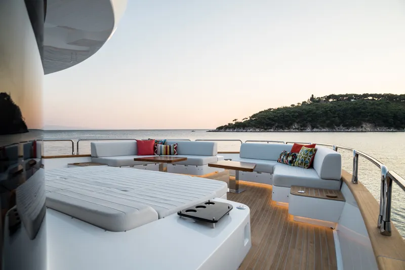 Slide: The Image of Luxurious Sirena 78 yacht deck with elegant seating, overlooking serene ocean and island, 2027 model. - 14