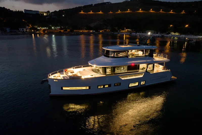Slide: The Image of Luxurious Sirena 78 yacht illuminated at night, reflecting on calm waters, 2027 model. - 9